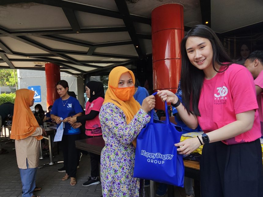 Steffiani Setyadji membagikan beras kepada masyarakat sekitar lokasi outlet Happy Puppy di Jalan Mayjend Sungkono.