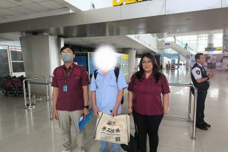 Petugas mengawal LW, Warga Negara China di Bandara Internasional Juanda untuk dipulangkan ke negara asal.
