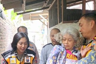 Kasatbinmas Polrestabes Surabaya Kompol Joes Indra menggendong seorang lansia warga disabilitas ke bilik suara.