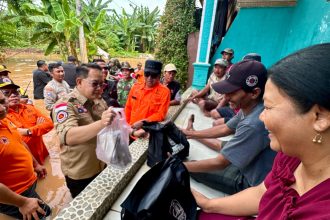Pj Gubernur Jatim Adhy Karyono menyerahkan bantuan kepada korban banjir didampingi Kalaksa BPBD Jatim Gatot Soebroto.