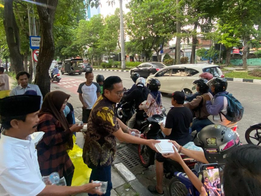 Ketua Partai Golkar Surabaya, Arif Fathoni membagikan ta'jil kepada pengguna jalan yang melintas di depan kantor partai.