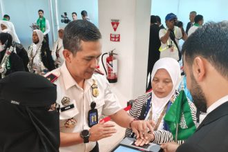 Kepala Kantor Imigrasi Kelas I Khusus TPI Surabaya, Agus Winarto, membantu jemaah haji siang sidik jari sebagai bentuk pengecekan dokumen secara digital.