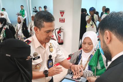 Kepala Kantor Imigrasi Kelas I Khusus TPI Surabaya, Agus Winarto, membantu jemaah haji siang sidik jari sebagai bentuk pengecekan dokumen secara digital.